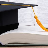 Black graduated tassel cap placed on the book.